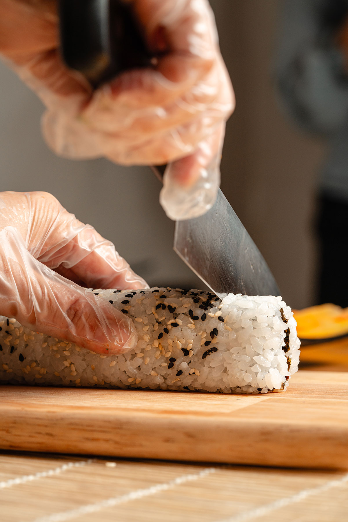 The chef's hands slicing a sesame-crusted roll